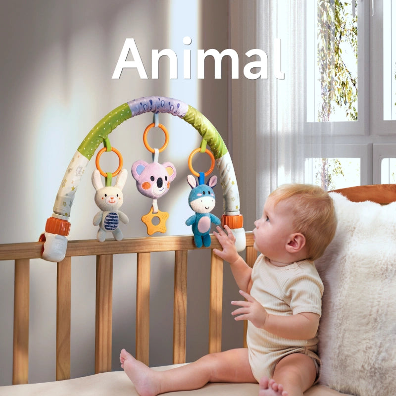 A baby sitting in a crib reaching for an animal-themed arch toy. The toy features plush characters, including a bunny, koala, and donkey, along with a star-shaped teether, securely attached to the crib for interactive play.
