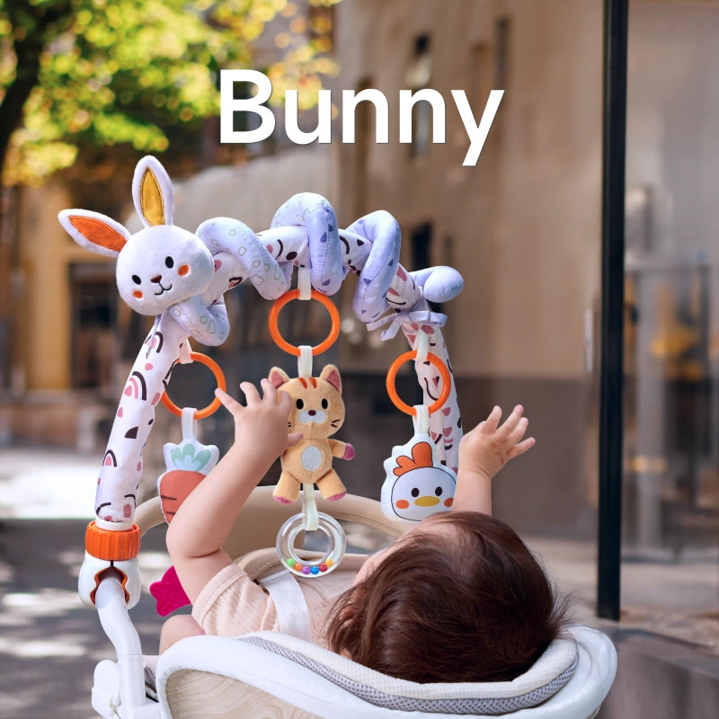 A baby lying in a stroller, reaching up to play with a bunny-themed arch toy. The toy features a cute bunny, cat, chick, carrot, and bead rattle, securely attached to the stroller for interactive fun.