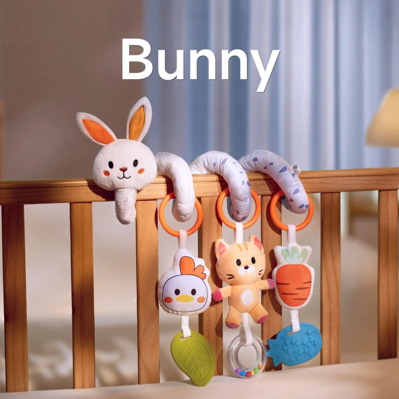 A bunny-themed spiral baby toy attached to a crib, featuring a plush bunny, chick, cat, carrot, leaf-shaped teether, and bead rattle. Perfect for engaging your baby during playtime.