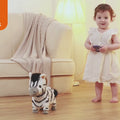 Little girl playing with electronic plush zebra toy indoors