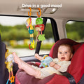 A baby sitting in a car looking at a frog lion toy hanging from the car